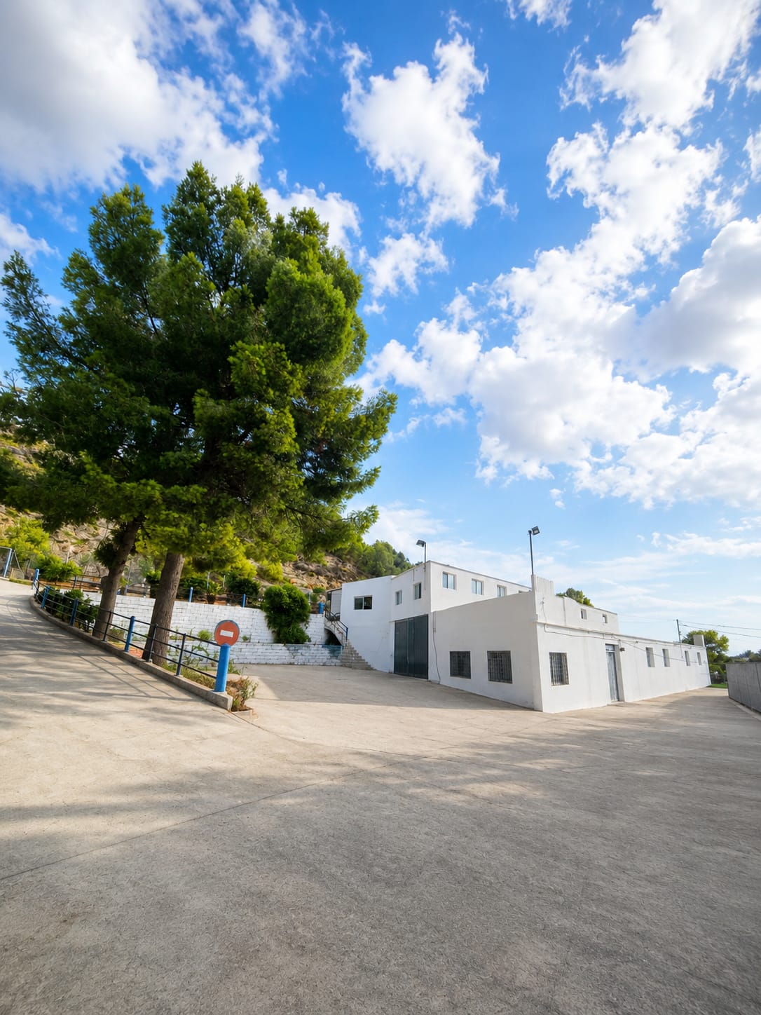 Entrada al centro Real Dog, con el edificio blanco y pinos